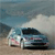 Pixelated static image of a light blue car on a sandy beach with a cloudy sky background.