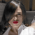 A pixelated close-up of a person with dark hair wearing a white top, red lips, and a silver bracelet, set against a blurred background.