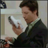 A man in a dark suit and light green shirt holds a white shoe with black accents, examining it closely