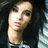 Pixelated static image of a person with light skin tone, dark hair, and a neutral expression, wearing a dark top with light accents.