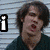 Pixelated image of two people with overlaid text, one person in dark clothing and light pants holding a guitar-like object against striped background.