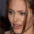Pixelated close-up of a person with light brown hair, visible eyes, nose, mouth, and ear, against a dark background with a lighter vertical element.