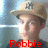 A person wearing a beige cap with a dark logo, red text reading "Robbie Is The Shit!" overlaid on a blurred background.