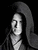 Static grayscale icon of a stylized figure with long flowing hair against black background, rendered in low-resolution pixel art style with visible dithering and anti-aliasing effects.