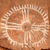 A pixelated circular design with radiating lines on a brown background, resembling a stylized sun or wheel with a central dark spot.