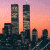 Pixelated cityscape with twin towers against a pink-orange sky, adjacent to green text reading 'Original Icons .com' on dark background.