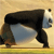 A pixelated panda in profile view, black and white fur, standing on a yellowish ground with a light brown background.