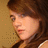 Pixelated close-up of a person with brown hair against a beige background, showing partial facial features and clothing details.