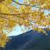 Pixelated landscape with golden-brown trees, light blue sky, and dark blue water, rendered in low-resolution mosaic style.