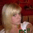 Pixelated image of a person with light brown hair and pinkish skin tone, wearing a white top with green text reading 'me!!' against a dark red background.