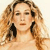 A pixelated close-up of a person with long wavy light brown hair, closed eyes, and dark earrings against a light background.