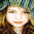 Two identical pixelated figures with long brown hair and green headwear, each wearing a white necklace, positioned side-by-side against a blurred background.