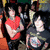 A pixelated image shows a group of people in the background with two individuals prominently visible, one wearing red and another black shirt, while text below reads "Escape the Fate".