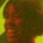 Extremely pixelated static icon with indistinct orange and yellow shapes against a dark green background, lacking clear subjects or text.