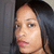 Pixelated close-up of a person's face with dark hair, light skin tone, and pink lips against a gray background.