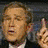 Pixelated static image of a person with light brown hair wearing dark clothing, making a hand gesture near their face against a blurred background.