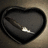 A heart-shaped icon with a dark gray interior and black border, featuring a diagonal light gray line with a bright white tip on the right side.
