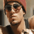 Pixelated static image of a person with dark hair and sunglasses, wearing a black top against an indoor background with red and beige tones.