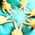 A pixelated static image with a central light blue star shape surrounded by four curved golden-yellow and teal elements on a gradient background.