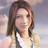 Pixelated static image of a person with shoulder-length brown hair wearing a white top against a blurred light background.