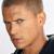 Pixelated close-up of a person's face showing short brown hair, light skin tone, and dark clothing against a bright background.