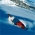Pixelated static icon of a person skiing on blue water with white and red elements against a light blue sky background.
