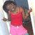 A pixelated figure in a red tank top and pink skirt stands with arms raised against a blurred background.