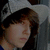 A pixelated image of a person wearing a light gray cap and dark hair, with visible text overlay in the right