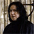 Static 50x50 pixel icon showing a person with dark hair and light skin wearing a black top against a blurred background of vertical lines.