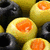 A split-screen image with olives on the left and text on a green background on the right.