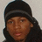 Pixelated close-up of a person wearing dark headwear and long hair against a light background.