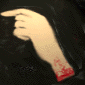 A hand with a red wristband points left against a dark background, transitioning to a curled fist position.