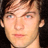 Static 48x48 pixel icon showing a close-up of a person's face with light brown hair, blue eyes, and neutral expression against dark background.