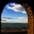 Pixelated landscape icon showing blue sky with white clouds, a brown tree trunk on the right, and a greenish-brown field below.