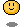 Pixelated yellow circular face with black outline, two vertical eyes and a smiling mouth on gray background.