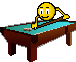 Pixelated yellow emoji figure with white eyes and black pupils leans over brown pool table with teal felt, holding cue stick poised to strike billiard balls.