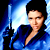 Pixelated static image of a person in blue attire holding a glowing object against a blue gradient background with black edges.