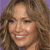 A pixelated close-up of a person with curly brown hair, light skin, and a smiling expression against a solid purple background.
