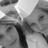 A grayscale pixelated image of two figures in close proximity, one with a light-colored head covering and the other with a dark vertical shape between them.