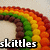 Rainbow-shaped icon with brown, green, yellow, orange, and red segments; text "skittles" in white, purple, and blue on bottom-left.