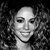 Black-and-white pixelated image of a person with curly hair, smiling, against a dark background.