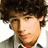 Pixelated close-up of a person with dark curly hair, light skin, and a red tie against a white background.