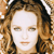 Pixelated close-up of a person with light brown curly hair, neutral expression, and no visible clothing or props.
