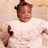 A child in a white dress with ruffled sleeves and a pink hair accessory poses against a light brown background, showing slight variations across frames.