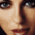 Pixelated close-up of a person's face showing eyes, nose, and mouth with warm skin tones and dark hair against a black background.