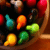 Pixelated static image of six colorful, teardrop-shaped objects arranged in two rows against a dark background with red and brown elements.