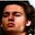 Pixelated close-up of a person's face with closed eyes, dark hair, and visible ear, set against a dark background with light accents.