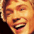 A pixelated image of a person with light brown hair and an open-mouthed smile, next to green text on a dark background.