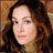 Pixelated close-up of a person with long dark hair against warm-toned background, static image.