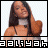 A 48x48 pixel animated contact sheet showing two side-by-side frames of a woman with long dark hair wearing a white top and black straps, smiling while touching her hair against a transparent background.